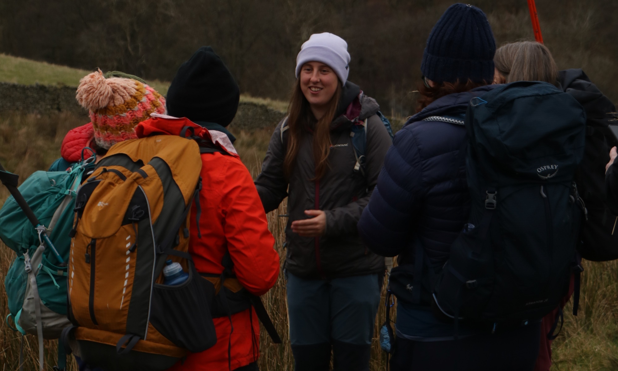 A woman talking to a small group all dressed for a walk.