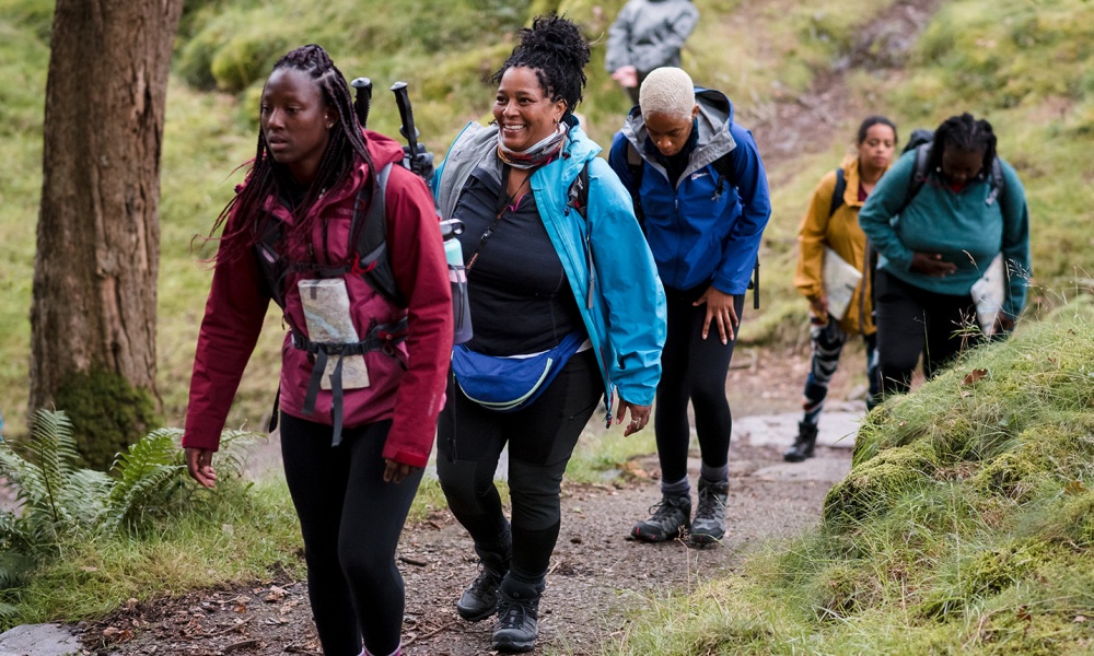 A group of black women hike through a woodland
