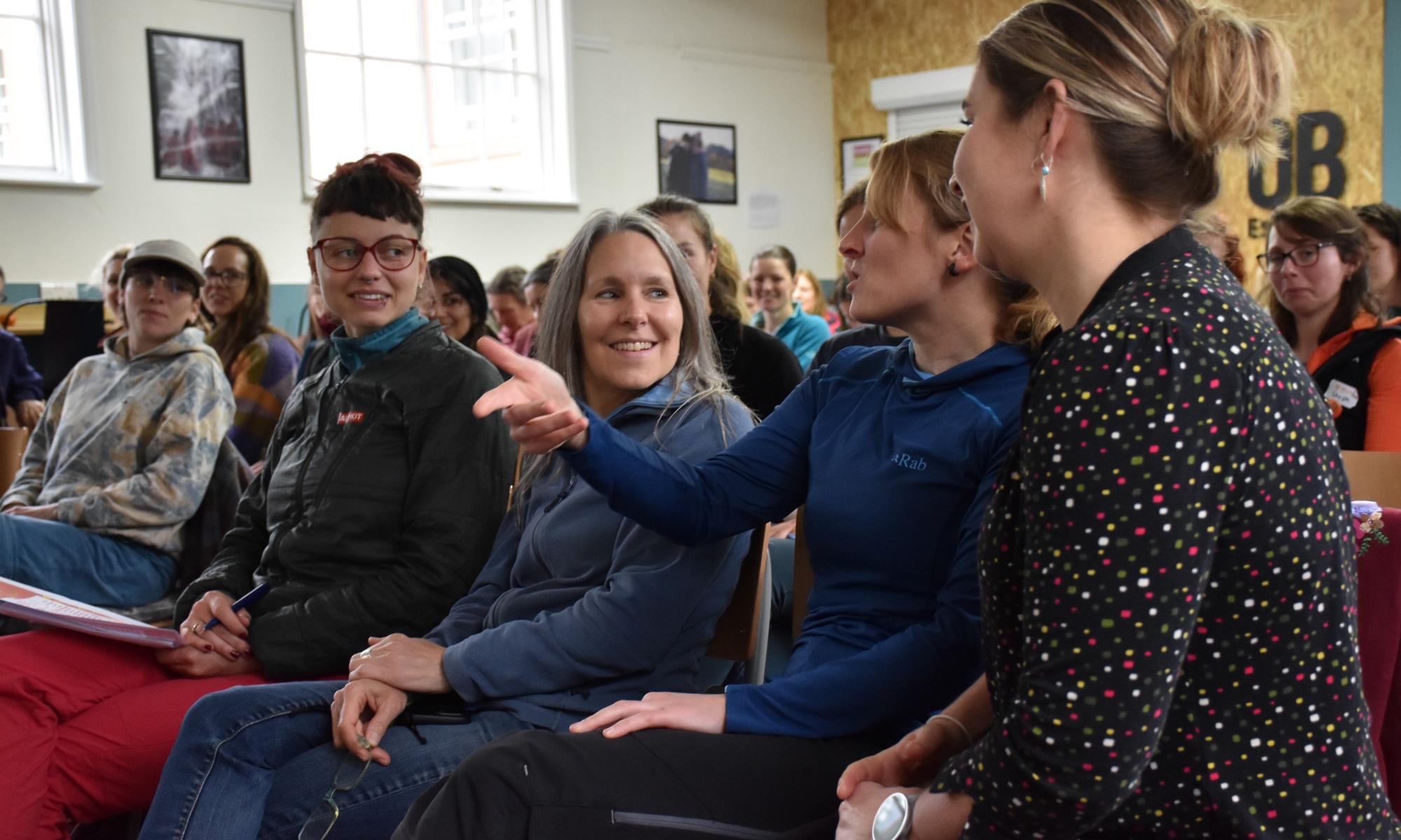 Lena Hunter gesticulating while talking next to Rachael Crewesmith in the main room at the conference.